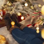 Lazy family parents and kid wearing warm woolen socks resting at home on cozy Christmas morning