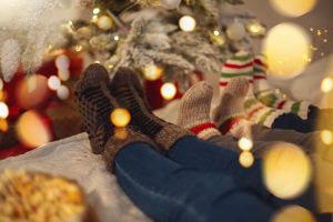 Lazy family parents and kid wearing warm woolen socks resting at home on cozy Christmas morning